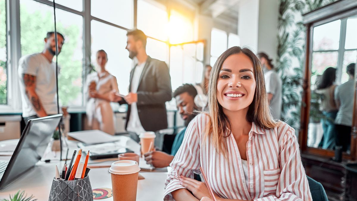 Smiling female employee sit in coworking space and working on the project. Front view