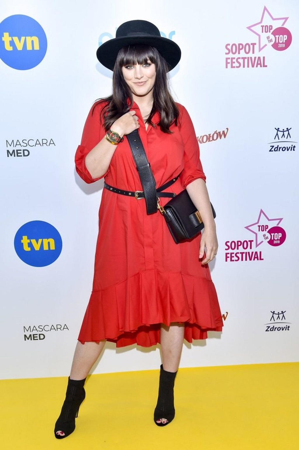 Ewa Farna w czerwonej sukience na ściance. 