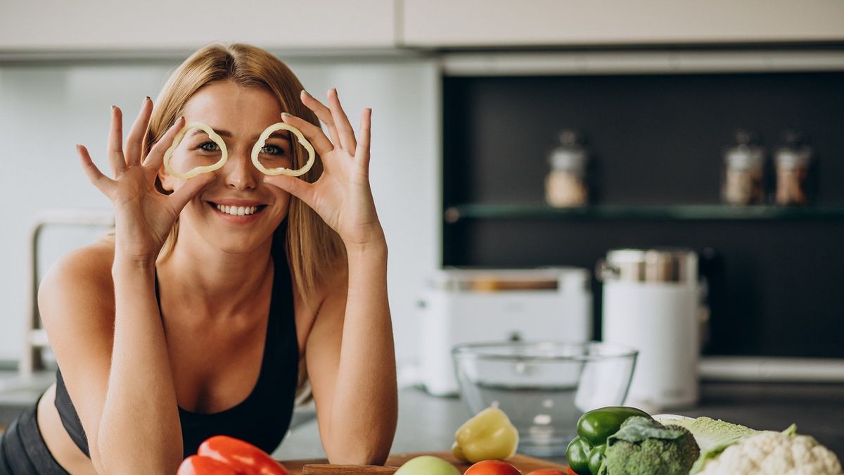 Young sporty woman with pepper at the kitchen