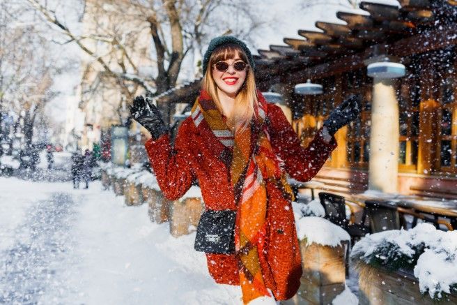 Happy winter time. Laughing woman playing with snow, having fun, enjoying holidays in European city.