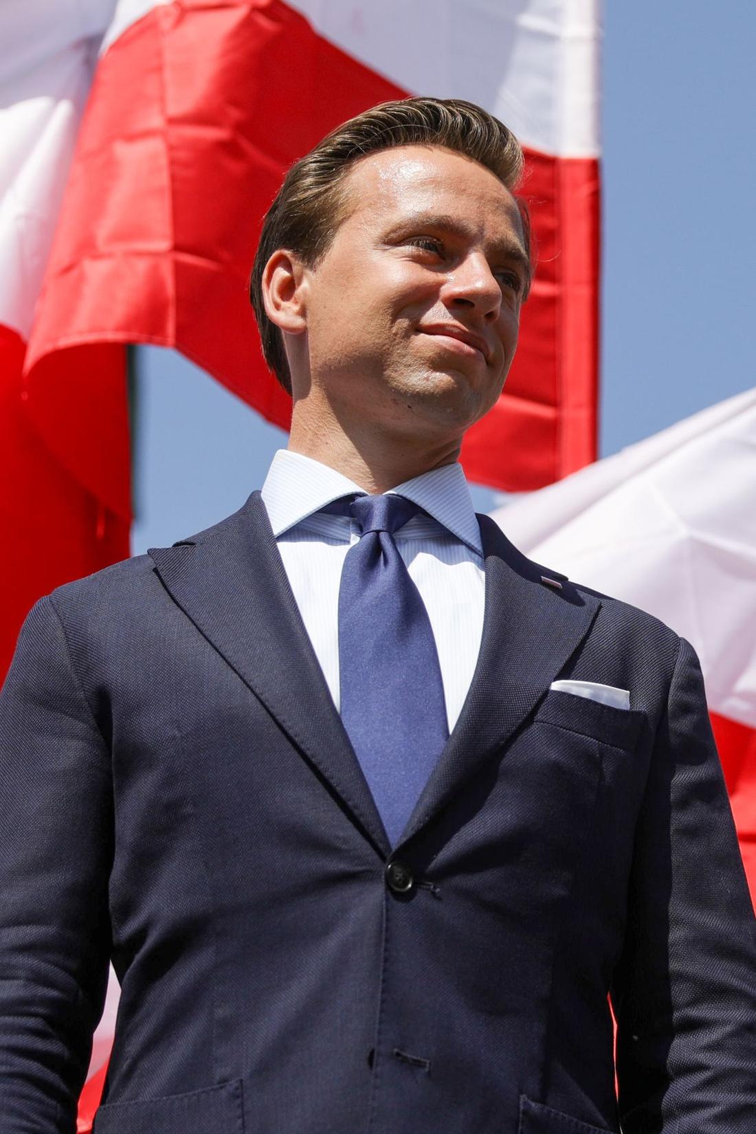 Krzysztof Bosak na tle flagi Polski